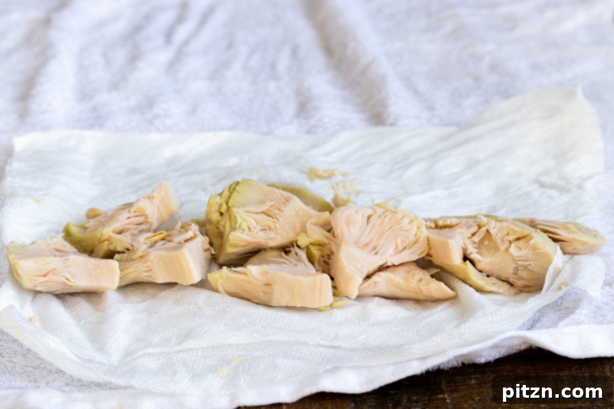 canned sliced of jackfruit being blotted dry on a sheet of paper towels