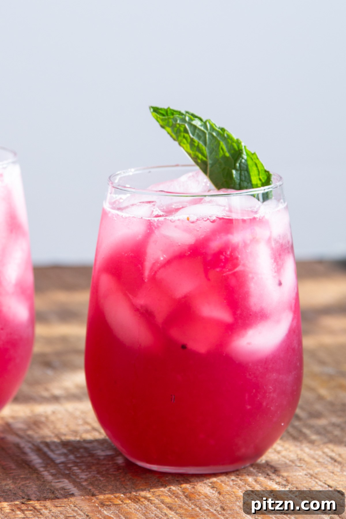 A single glass of blueberry lemonade garnished with a mint leaf, highlighting the vibrant color of the drink.