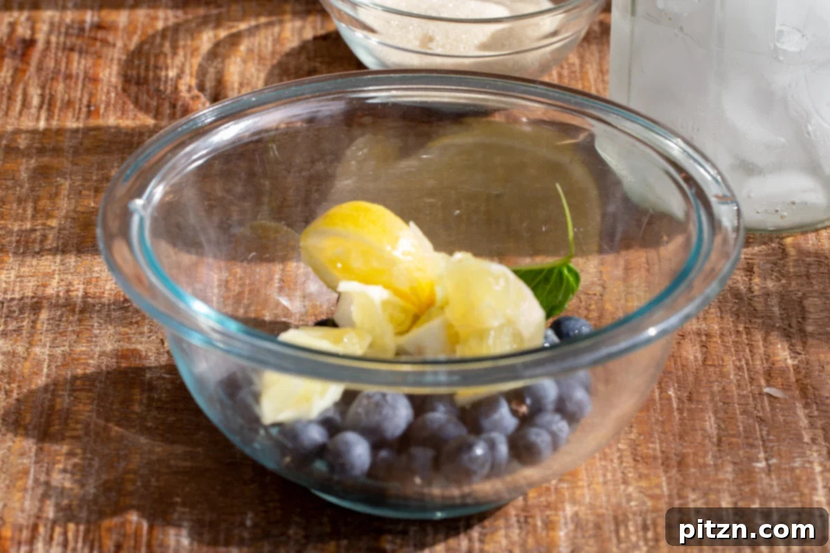 Fresh blueberries and lemon slices in a small glass bowl, ready for muddling.