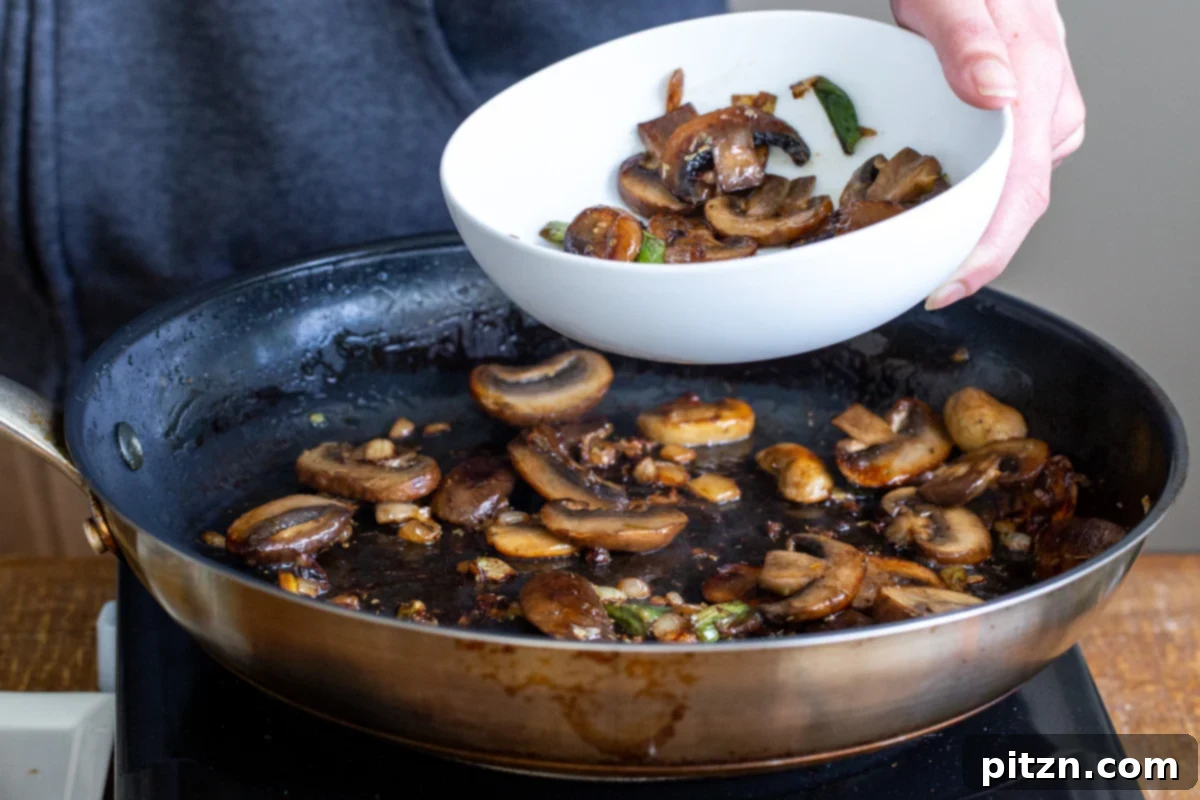 Perfectly golden-brown fried mushrooms resting in a skillet, ready to be partly reserved for topping.