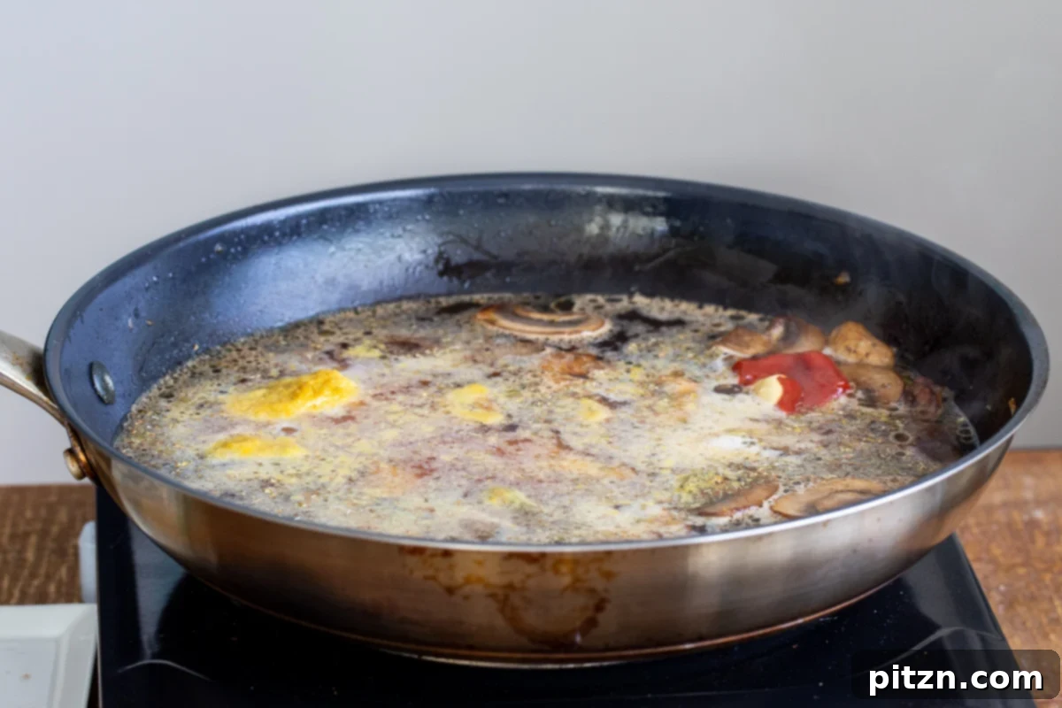 Mushrooms simmering in a savory broth within a dark skillet, creating the base for the lasagna sauce.