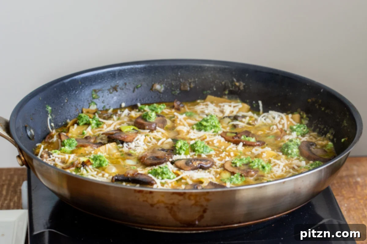 Golden-brown fried mushrooms and vibrant basil pesto being artfully added to a black skillet containing perfectly cooked lasagna noodles.