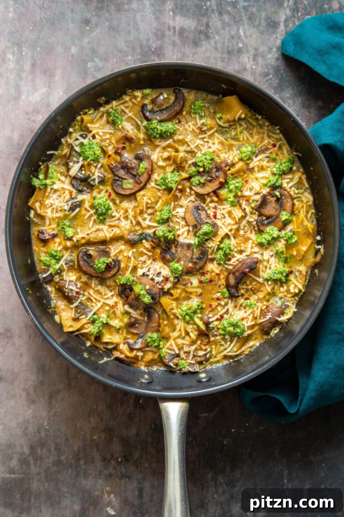 An inviting overhead shot of a black skillet showcasing the delectable vegan one-pan mushroom and pesto lasagna, fresh from the stovetop.