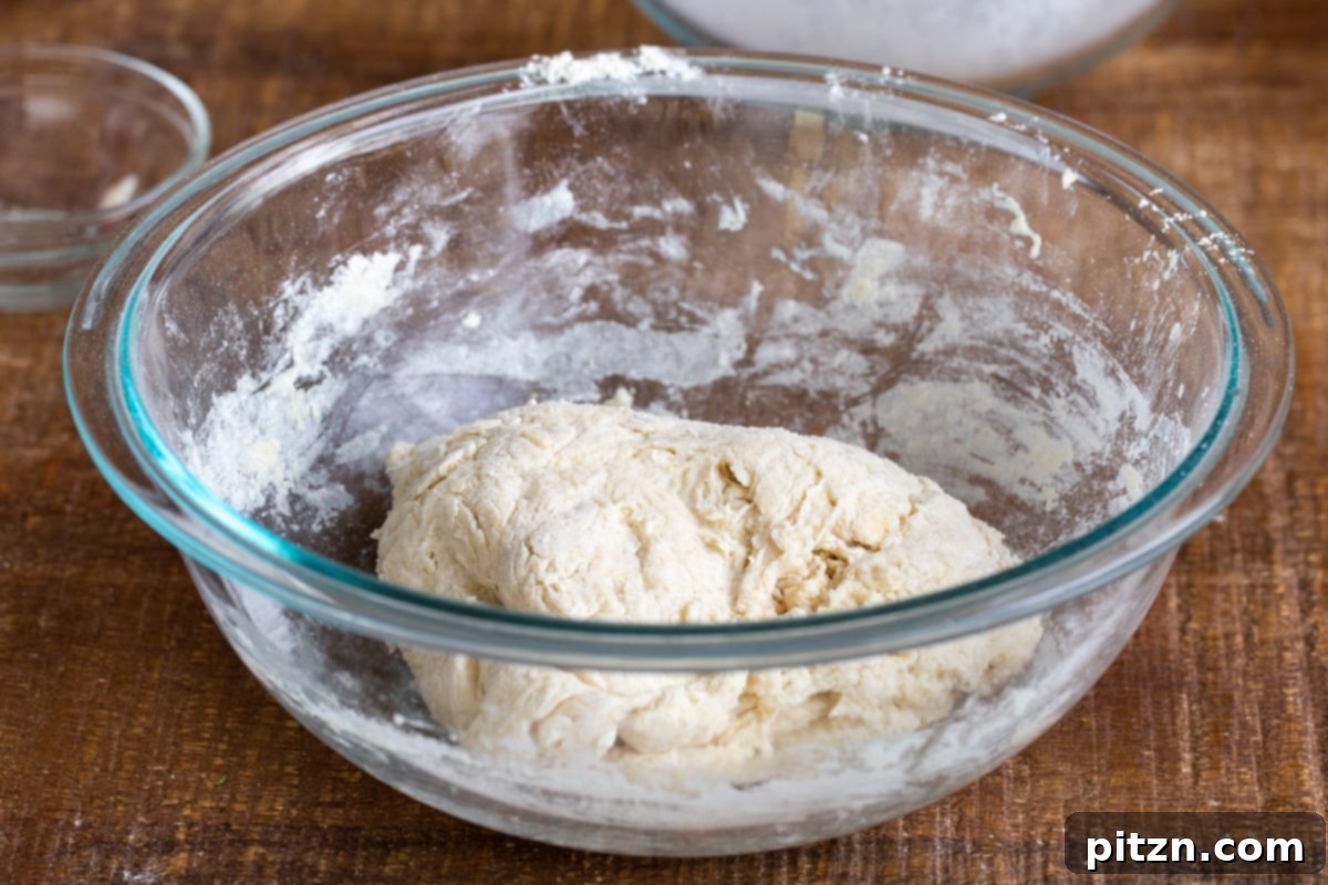 Deep Dish Pizza with a Pretzel Twist 11 A perfectly risen ball of pretzel crust pizza dough nestled in a clear glass bowl, showcasing its airy and expanded texture after fermentation.