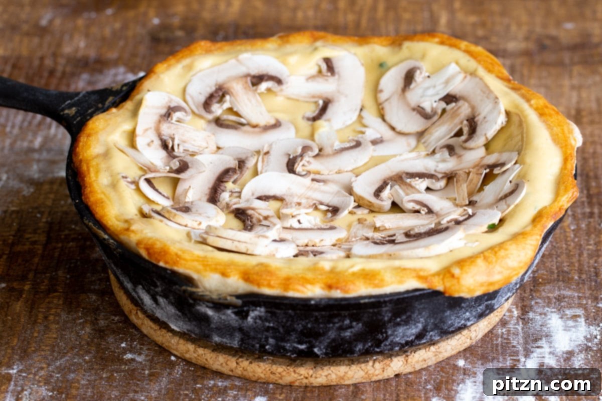 Deep Dish Pizza with a Pretzel Twist 15 A prebaked vegan deep dish pizza crust, generously topped with creamy vegan cheese sauce and a layer of uniformly sliced mushrooms, awaiting further toppings.