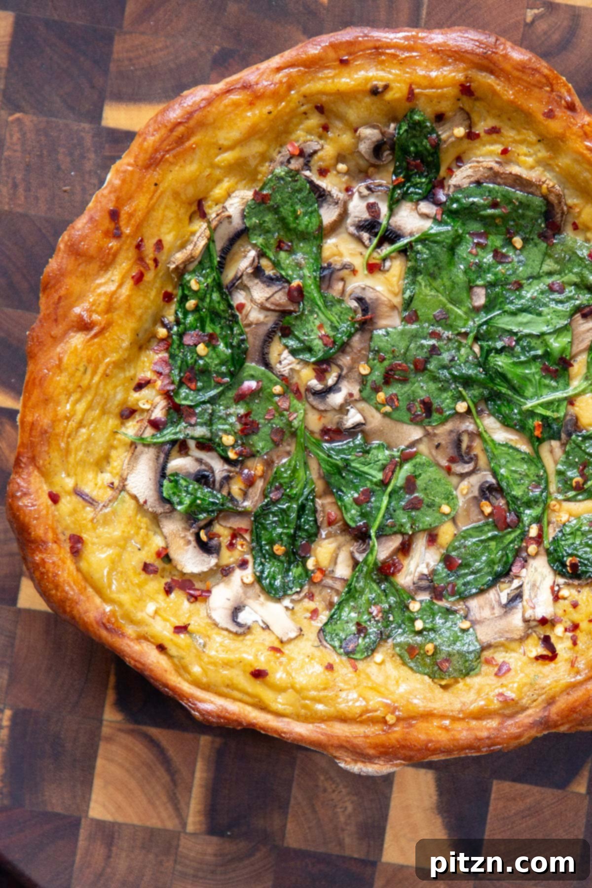 Deep Dish Pizza with a Pretzel Twist 3 A close-up shot of a magnificent vegan deep dish pretzel crust pizza, lavishly topped with melted vegan cheese sauce, vibrant spinach, and sliced mushrooms, ready to be served on a wooden board.