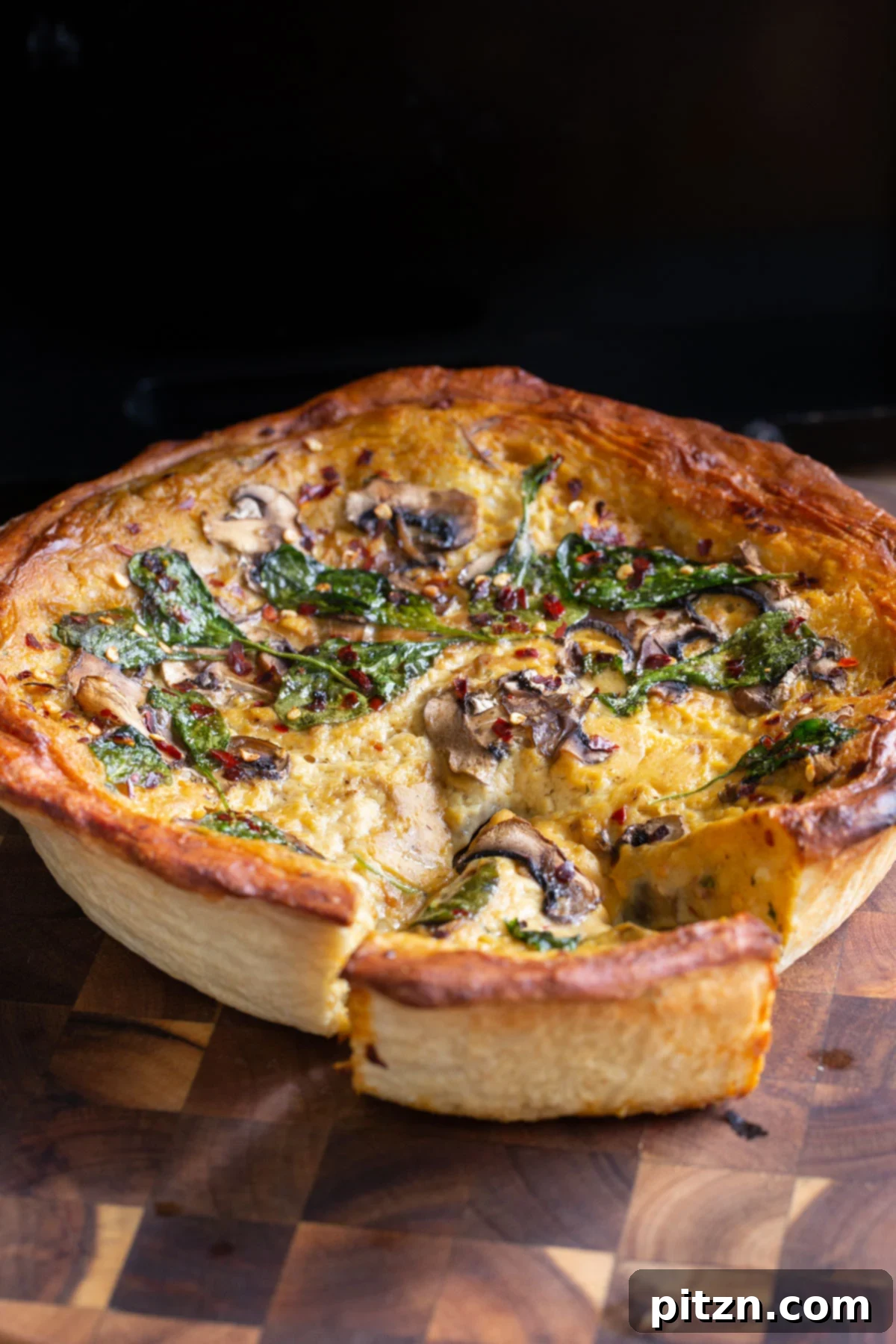 Deep Dish Pizza with a Pretzel Twist 4 An appetizing slice of vegan deep dish pretzel crust pizza showcasing its luscious cheese, fresh spinach, and tender mushroom filling on a wooden board, ready to be enjoyed.