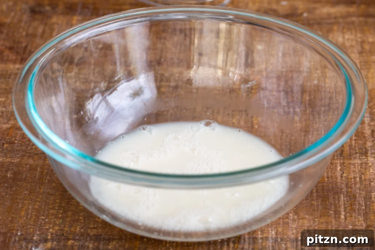 Deep Dish Pizza with a Pretzel Twist 9 A small glass bowl containing warm water, active yeast, and sugar, gently mixed and left to activate, forming a frothy top.