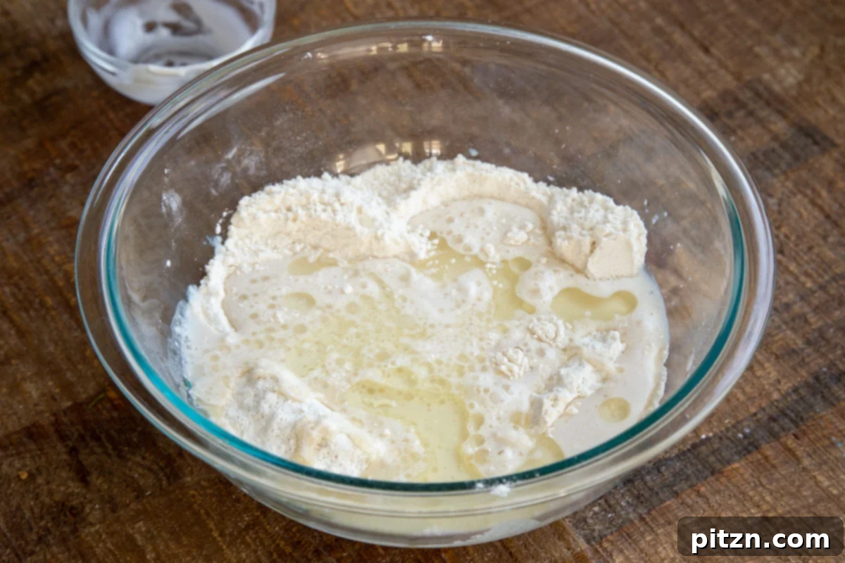 Plant-Based Tiramisu Tray Bake 10 Liquid ingredients being poured into the dry ingredients in a glass bowl, initiating the mixing process for the vegan cake batter.