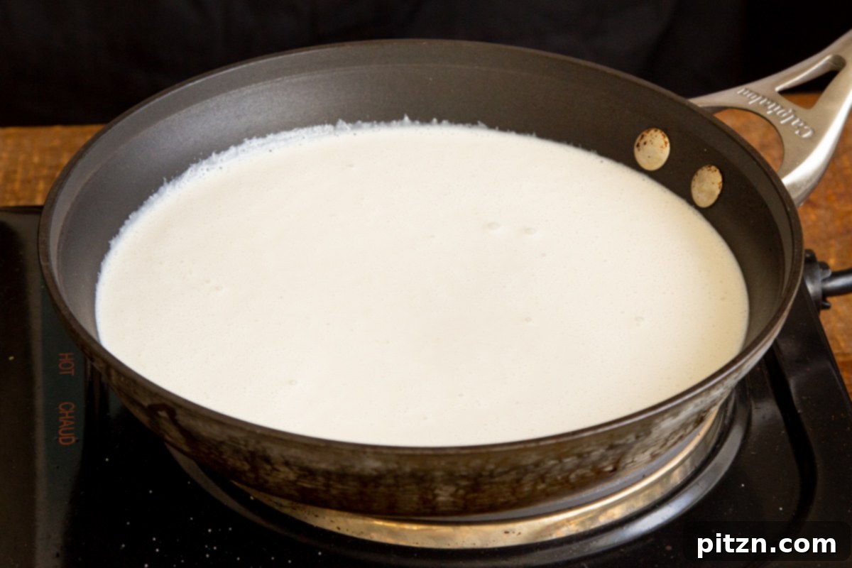 Plant-Based Tiramisu Tray Bake 17 Vegan mascarpone cheese gently cooking in a saucepan over medium heat, as it thickens to the desired creamy consistency.