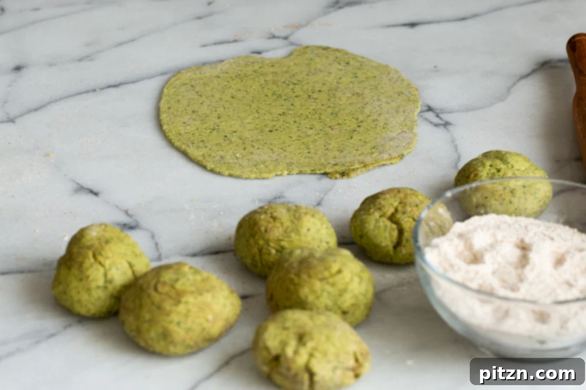 Aromatic Masala Paratha: Easy Yeast-Free Indian Flatbread 9 small rolled balls of paratha dough on a marble countertop with a small dish of flour on the side