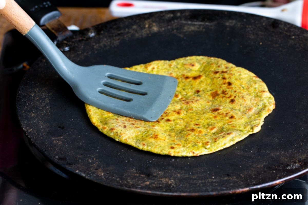Aromatic Masala Paratha: Easy Yeast-Free Indian Flatbread 14 an Indian flatbread being prepared in a black skillet