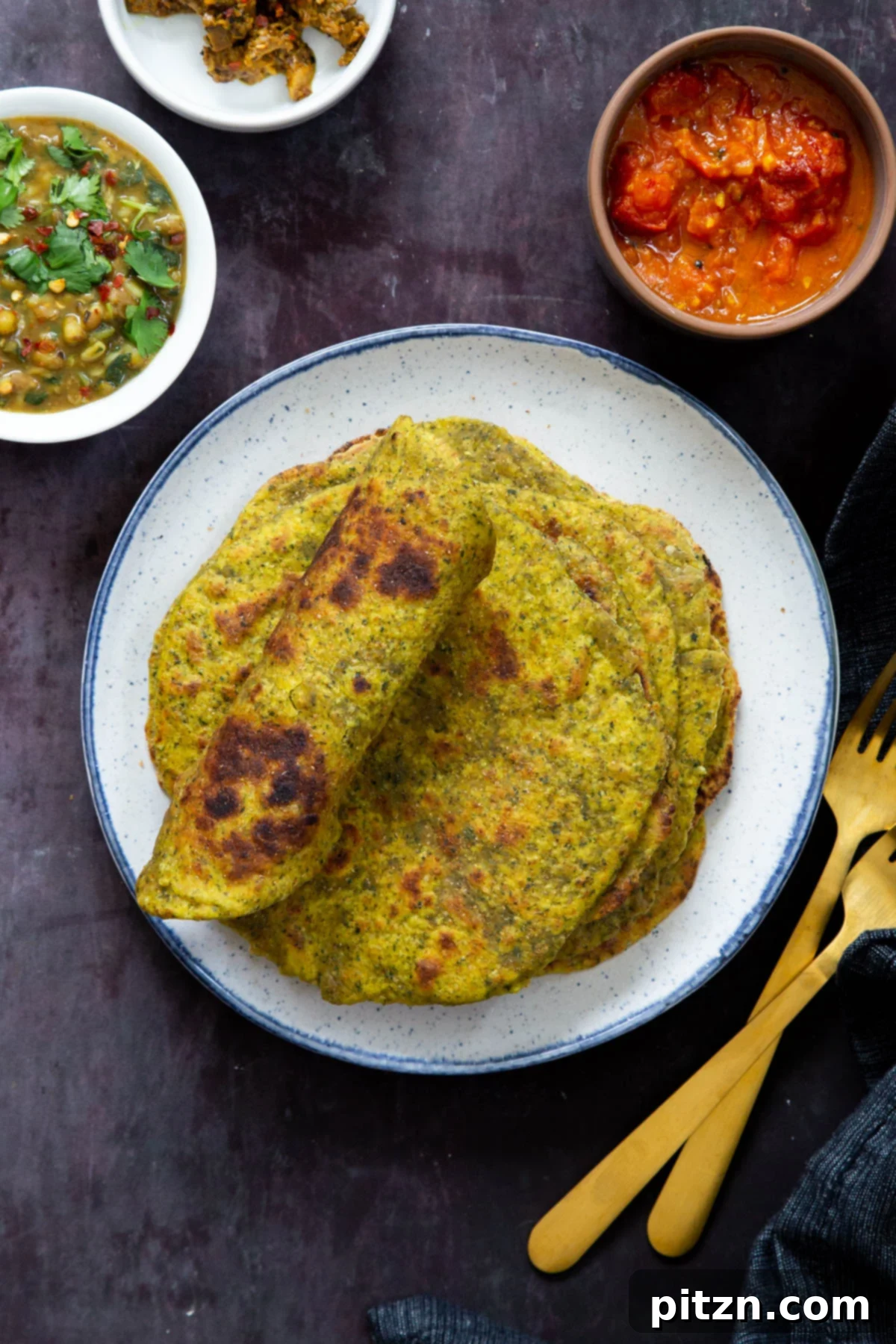 Aromatic Masala Paratha: Easy Yeast-Free Indian Flatbread 3 stacked masala parathas on a white plate with small side dishes on the side