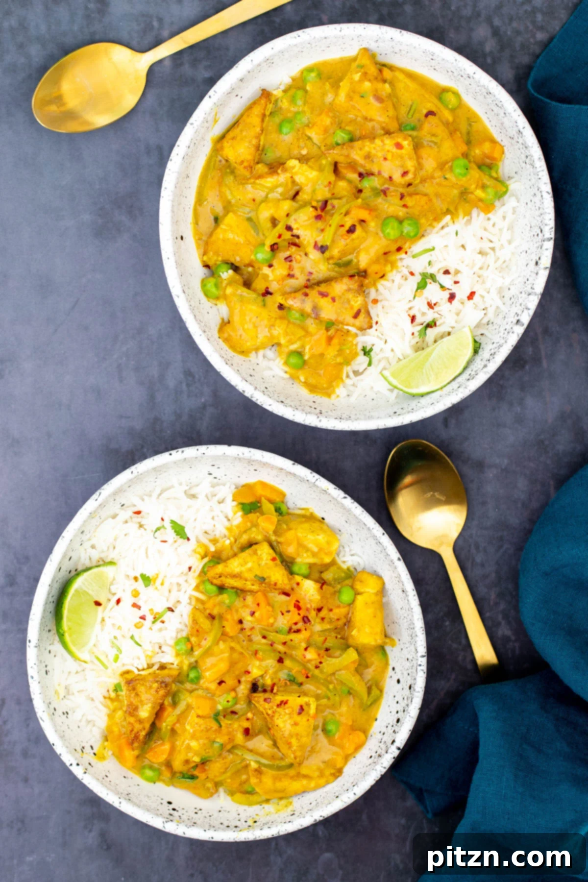 Vibrant Malaysian Tofu Curry 5 Two bowls with rice and Malaysian coconut tofu curry served with two golden spoons