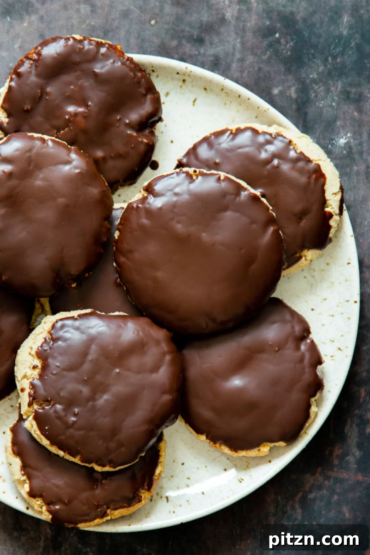 The Ultimate Vegan Gluten-Free Snickers Cookies 3 Close-up of vegan gluten-free Snickers cookies generously covered with chocolate glaze, showing their inviting texture and rich brown hue.