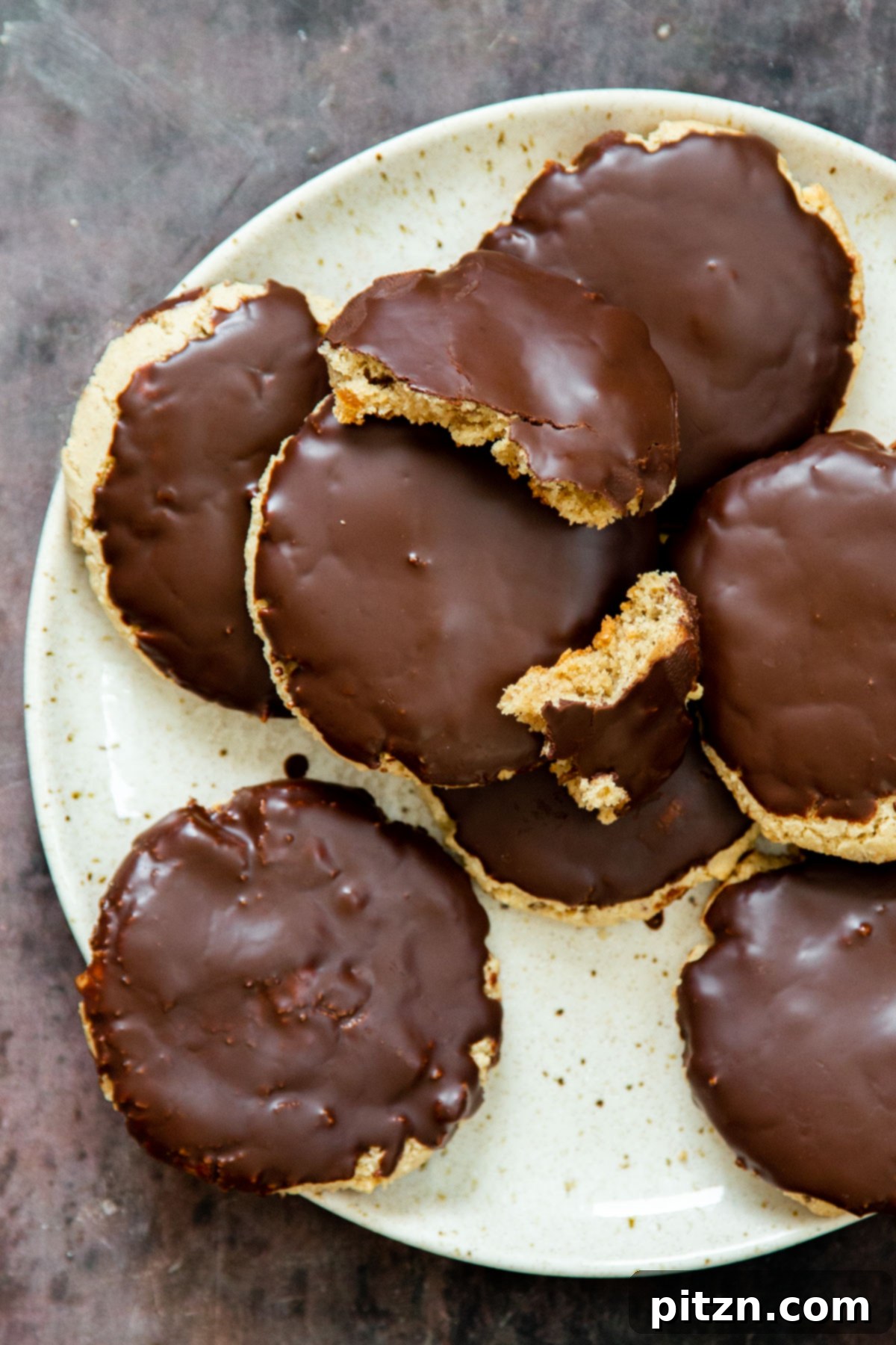 The Ultimate Vegan Gluten-Free Snickers Cookies 5 A beautifully arranged plate featuring several vegan gluten-free almond flour Snickers cookies, generously coated with a smooth chocolate glaze.