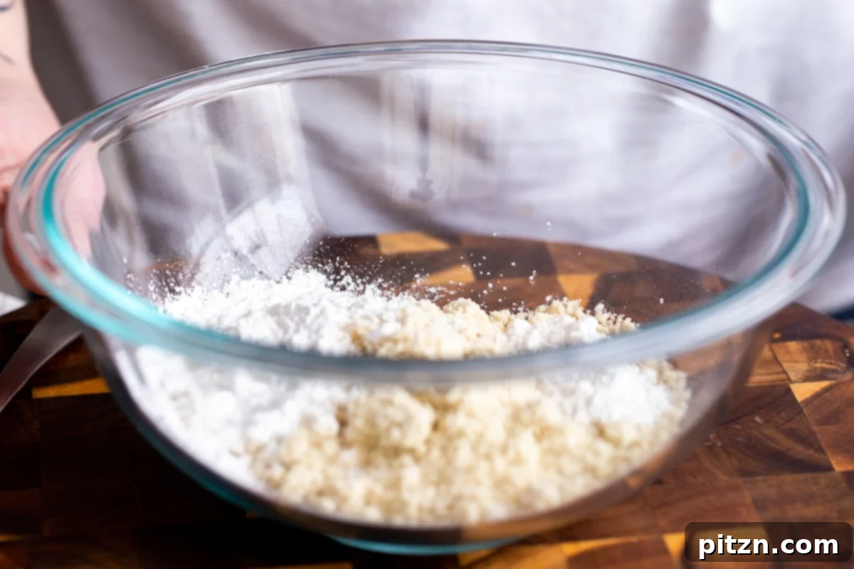 The Ultimate Vegan Gluten-Free Snickers Cookies 7 A transparent glass bowl containing almond flour and tapioca starch, essential dry ingredients for the vegan Snickers cookies.
