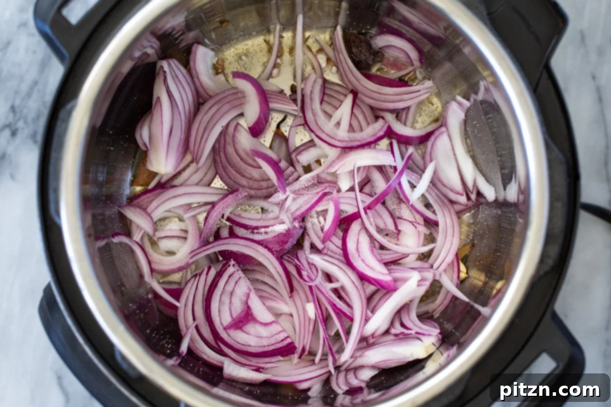 Fragrant Mushroom Biryani 10 Thinly sliced onions gently sautéing in an Instant Pot, beginning to caramelize to a golden color.