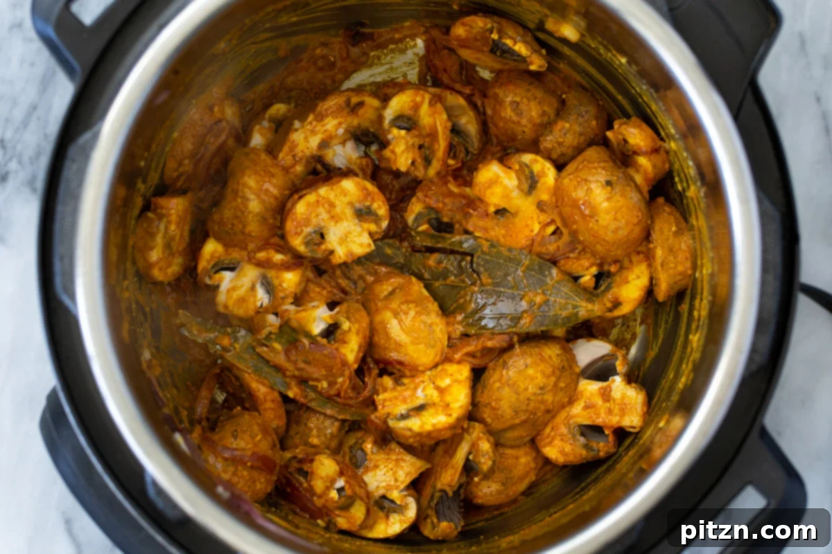 Fragrant Mushroom Biryani 15 Sliced mushrooms being tossed and coated in a rich Indian gravy within an Instant Pot.