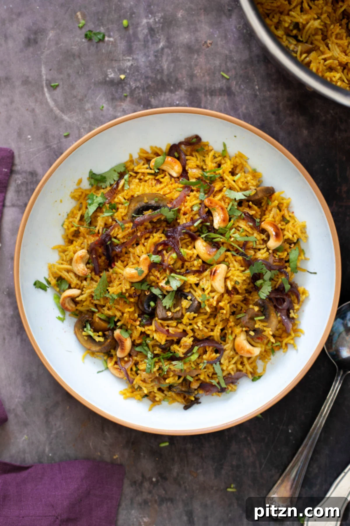 Fragrant Mushroom Biryani 4 A close-up of a serving of mushroom biryani, garnished with toasted cashews and fresh cilantro, highlighting its vibrant colors and textures.