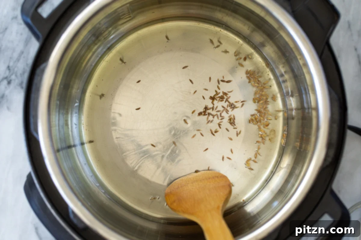 Fragrant Mushroom Biryani 7 Cumin seeds being tempered in hot oil within an Instant Pot, releasing their aromatic essence.