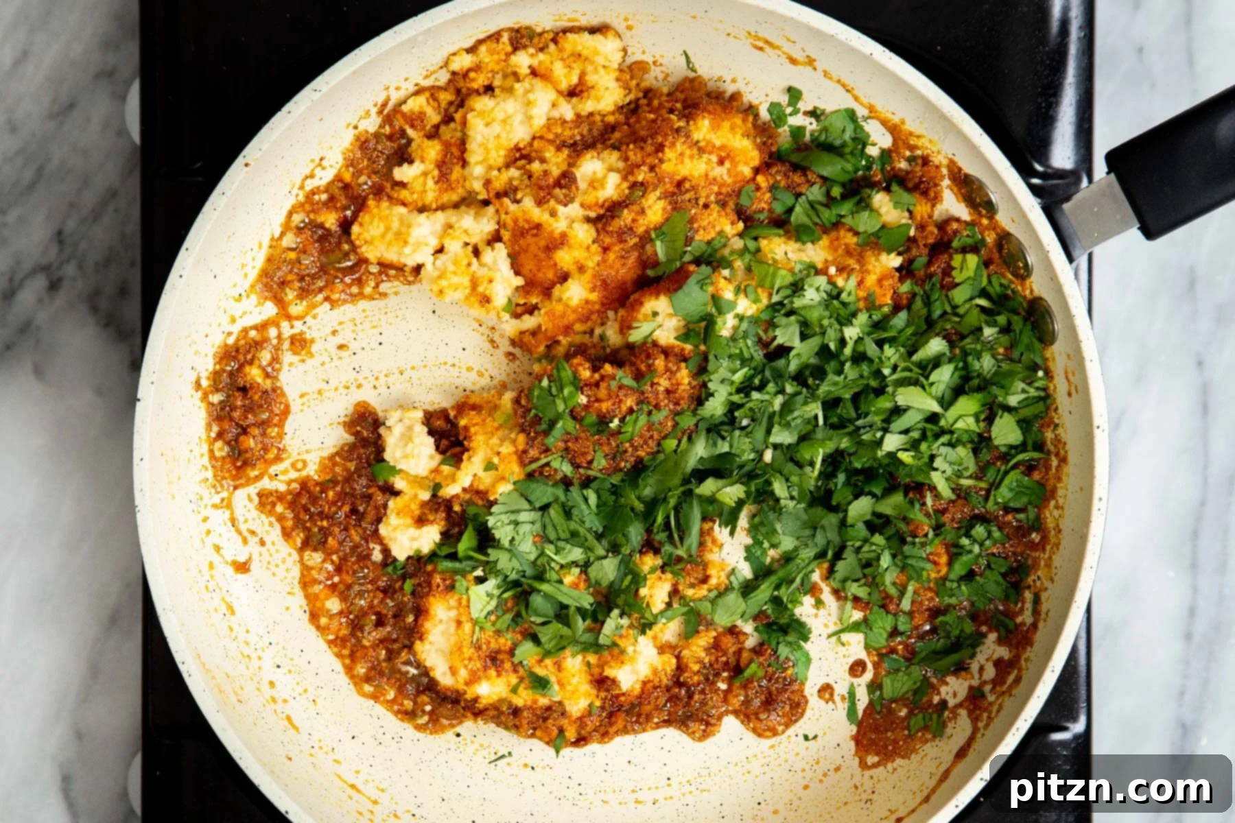 Coarsely ground urad dal, fresh cilantro, and the spice blend being mixed together in a sauté pan, forming the Kachori filling.