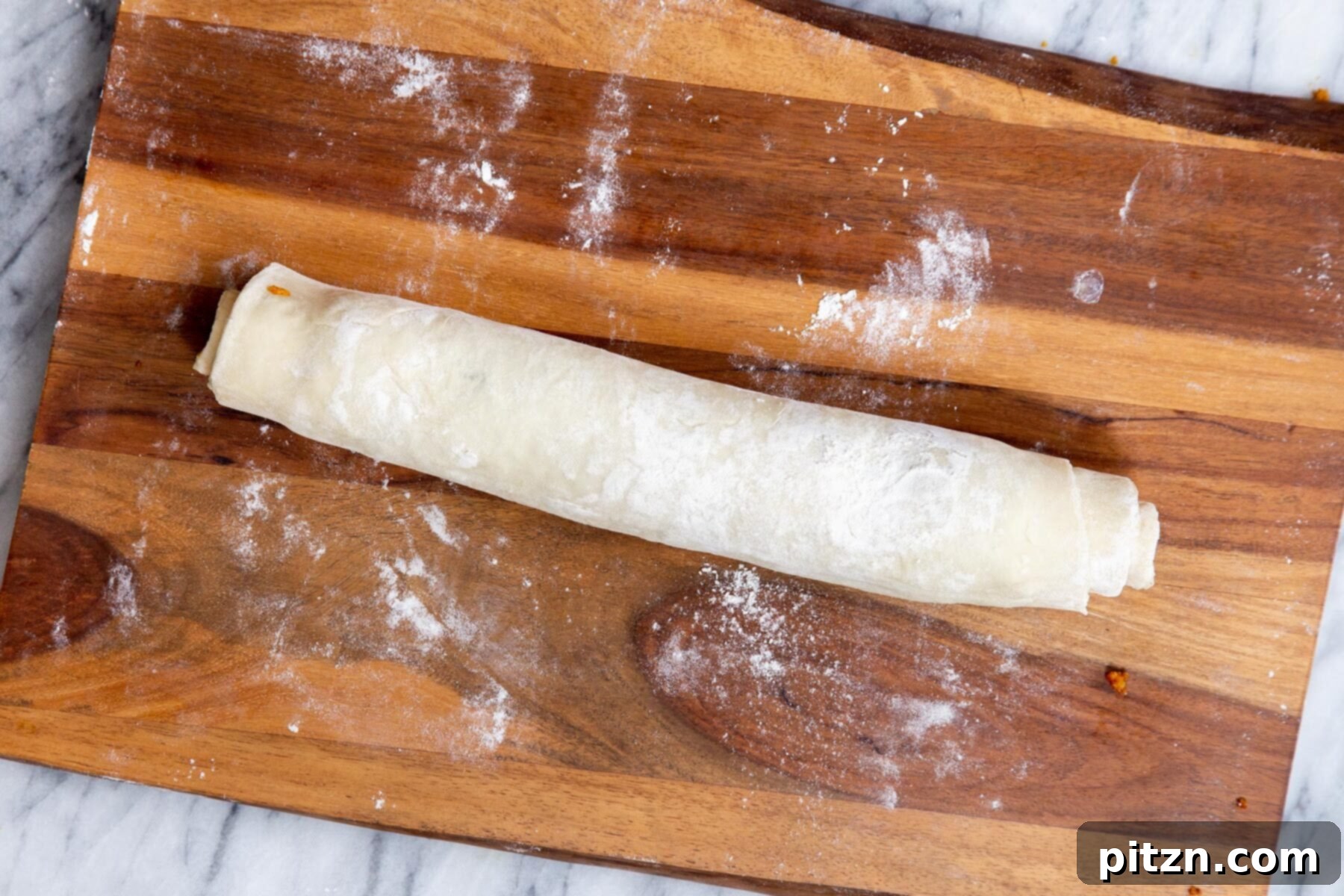 A perfectly rolled-up filled puff pastry log, ready for slicing into individual pinwheels.