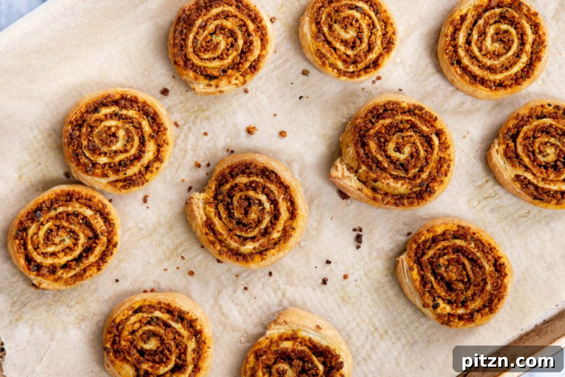 Freshly baked vegan kachori pinwheels straight out of the oven, glistening and golden on a sheet pan.