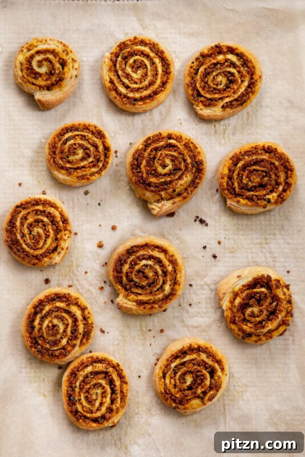 A vibrant display of freshly baked vegan pinwheels resting on a sheet of parchment paper, showcasing their perfect spirals and golden color.