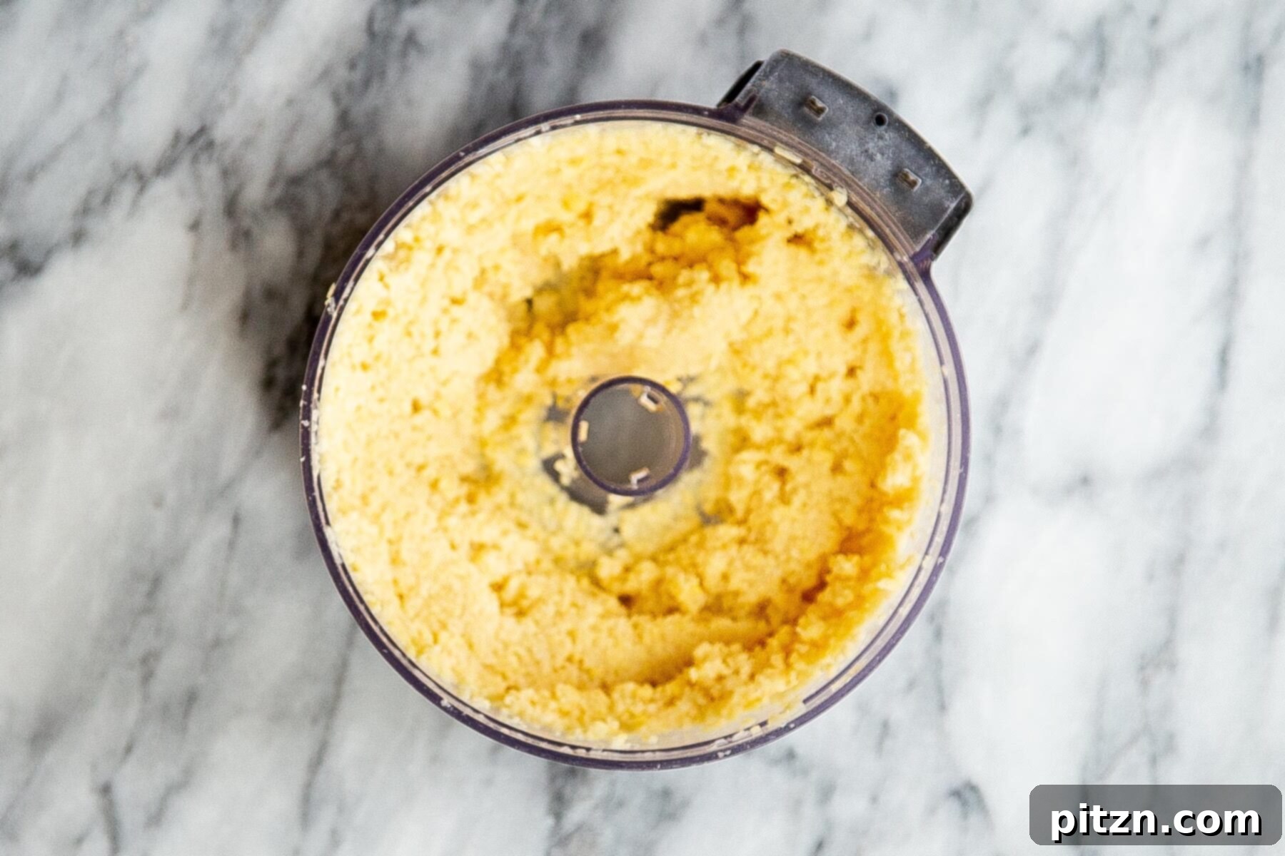 Blended urad dal in a food processor, showing its coarsely textured consistency, prepared for the filling.