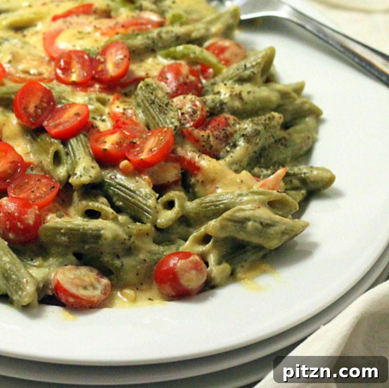 Close-up of creamy vegan pasta dish with spinach, red bell peppers, and cashews