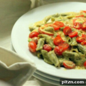 A white shallow bowl, filled with Spinach Penne with Red Bell peppers