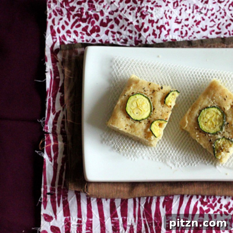 Naturally Gum-Free Vegan Gluten-Free Zucchini Basil Focaccia 3 Close-up shot of the Gluten-free Zucchini Basil Focaccia, showing the texture of the bread with baked zucchini slices and herbs.