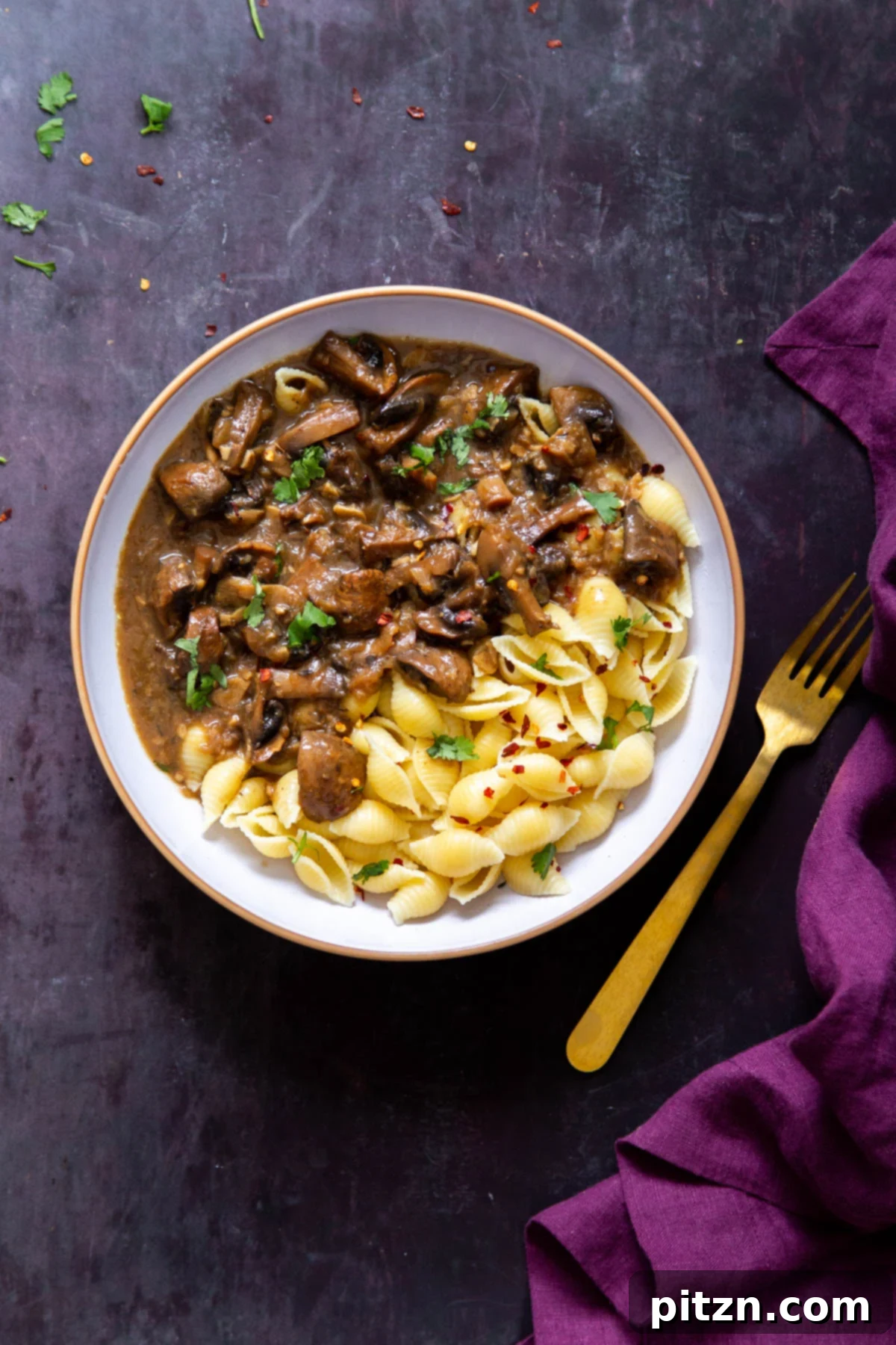 Instant Pot Garlic Mushrooms and shell pasta in a white bowl with a golden fork on the side, highlighting the dish's appeal