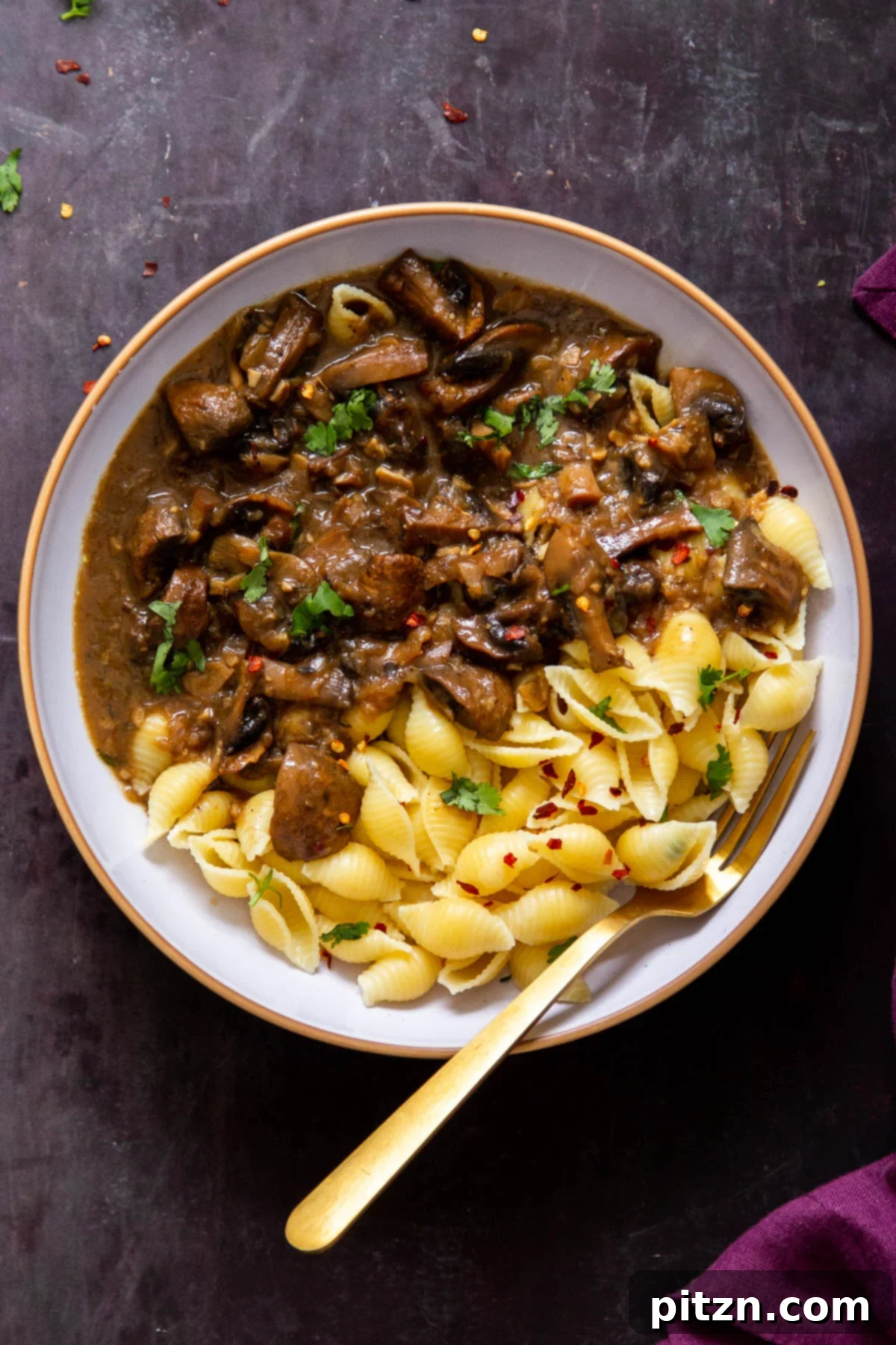 A white bowl showcasing delicious Instant Pot Garlic Mushrooms and pasta, with a golden fork resting on the side