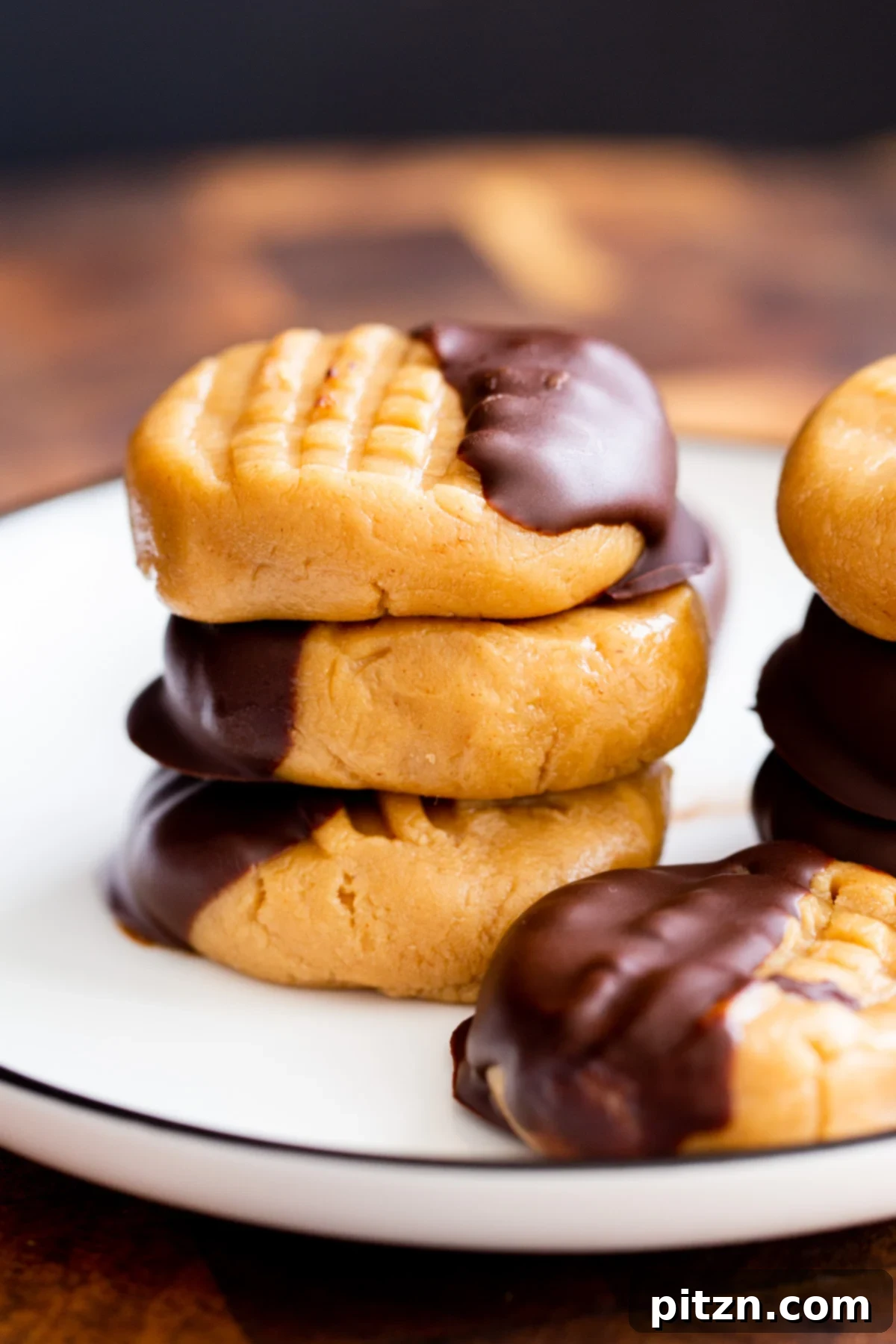 A beautifully arranged stack of no-bake peanut butter cookies, half-dipped in rich chocolate, on a delicate plate, ready to be enjoyed.