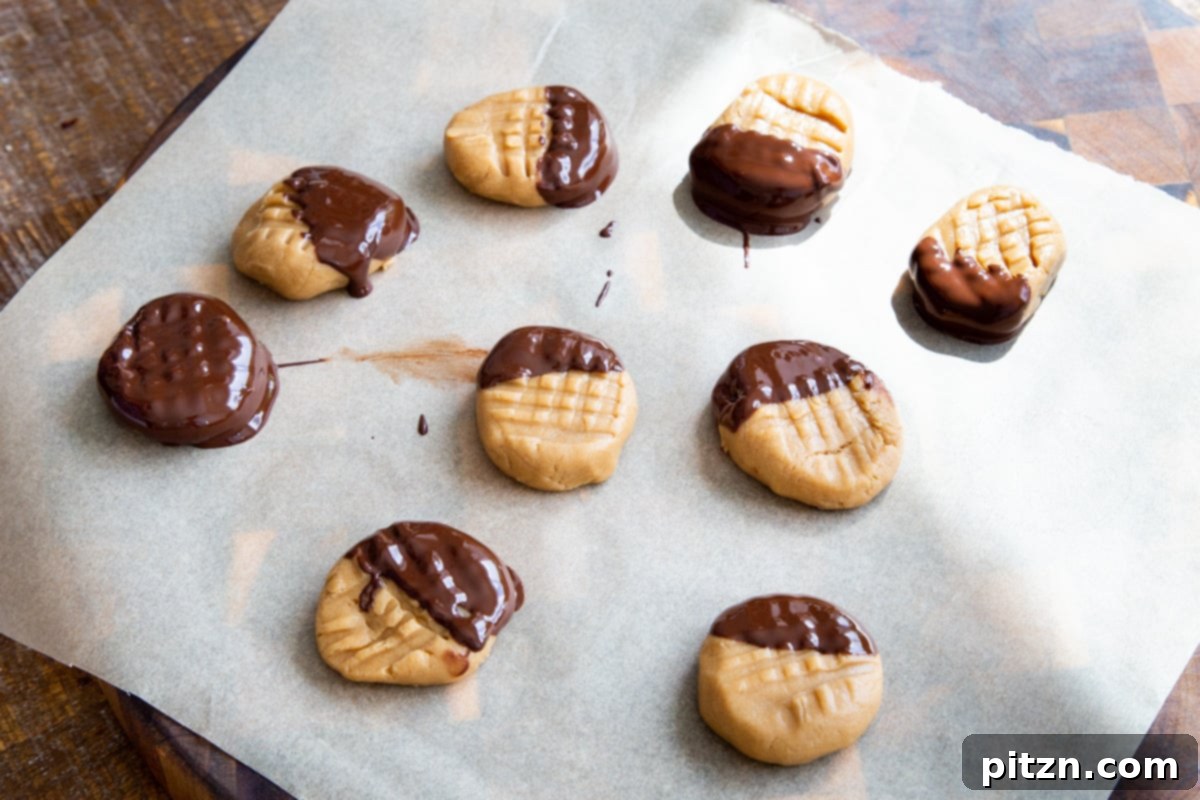 Delicious no-bake peanut butter cookies, freshly dipped in rich melted chocolate, arranged neatly on a sheet of parchment paper to cool and set.