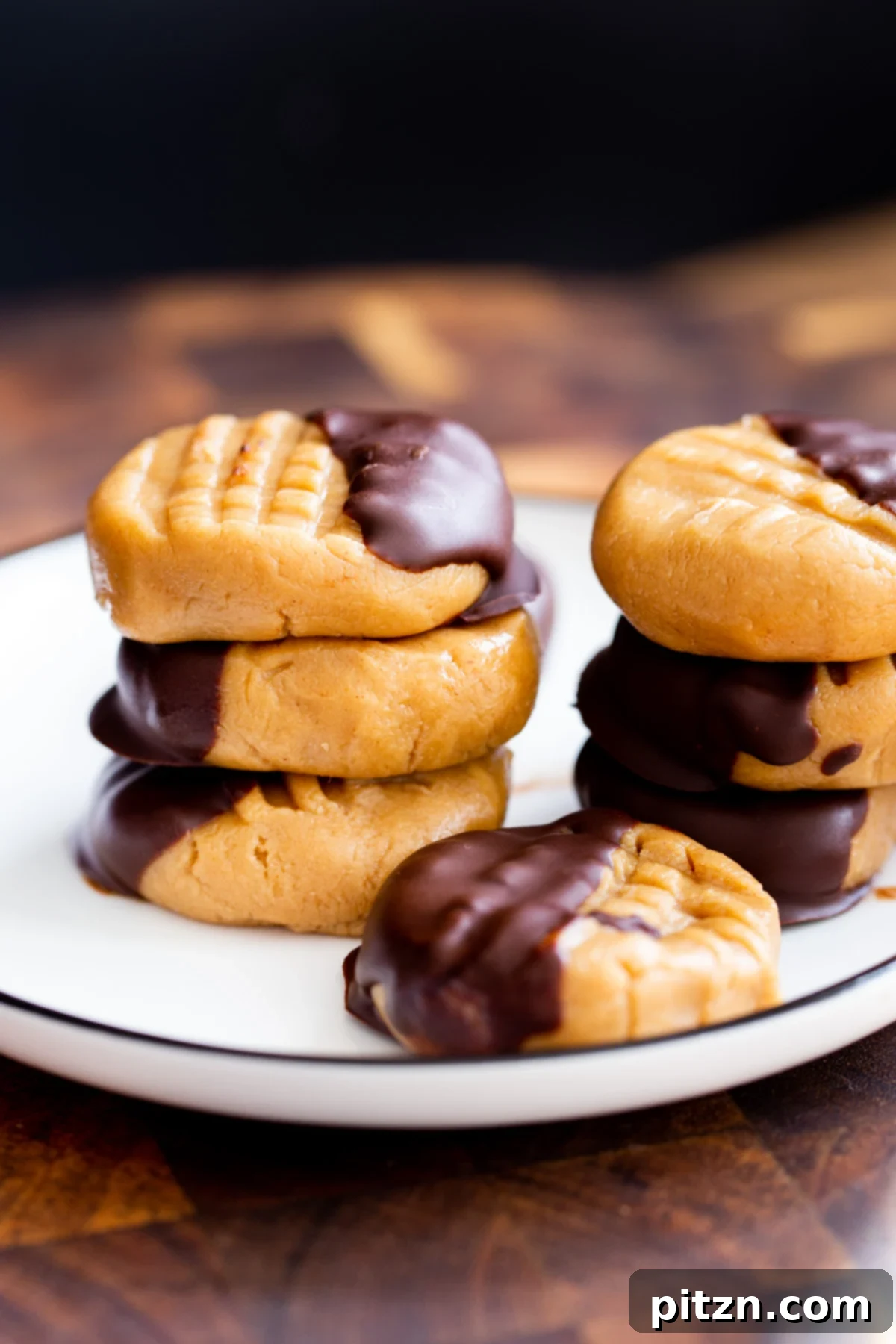 Two enticing stacks of no-bake peanut butter cookies, generously dipped in dark chocolate, artfully arranged on a white plate, showcasing their delightful texture.