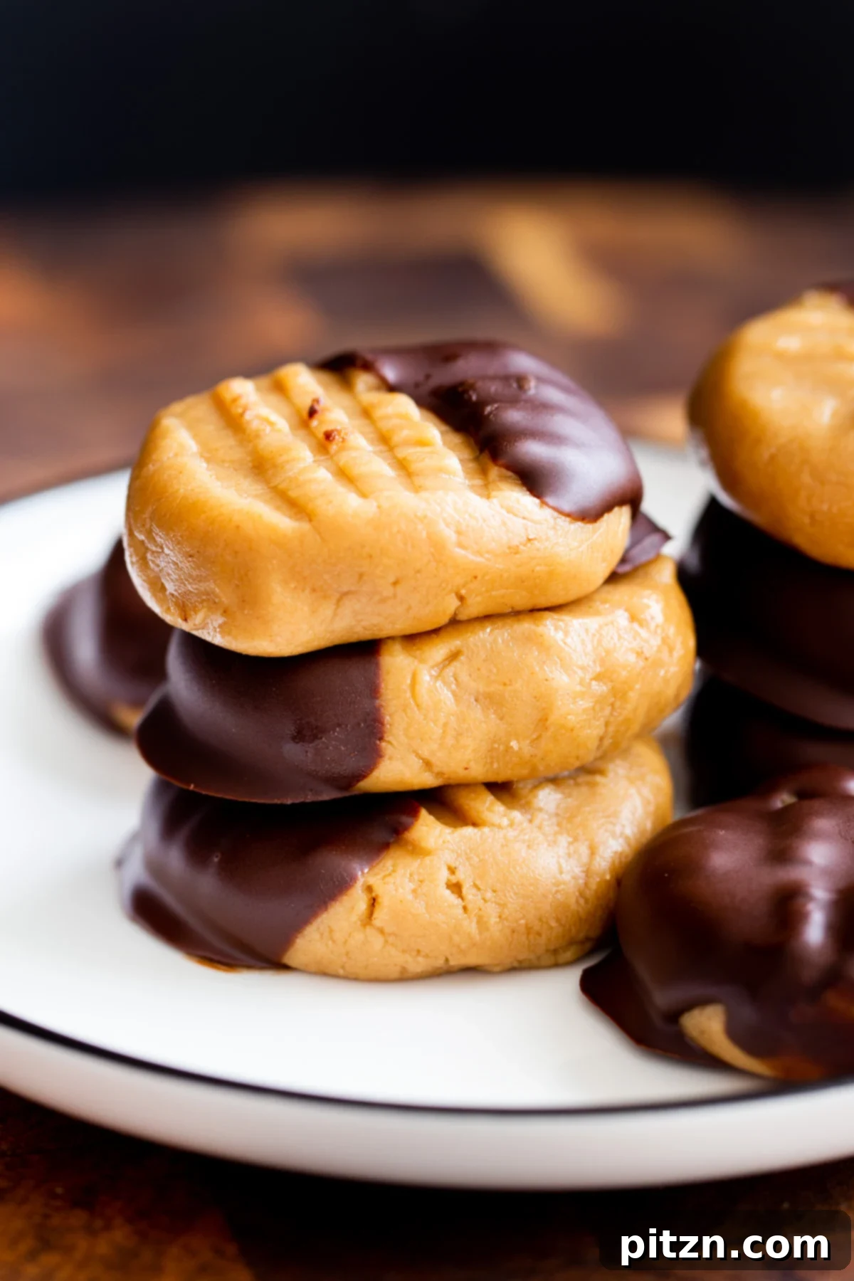 A perfectly stacked tower of vegan no-bake peanut butter cookies, expertly dipped in chocolate, presented on a minimalist white background.