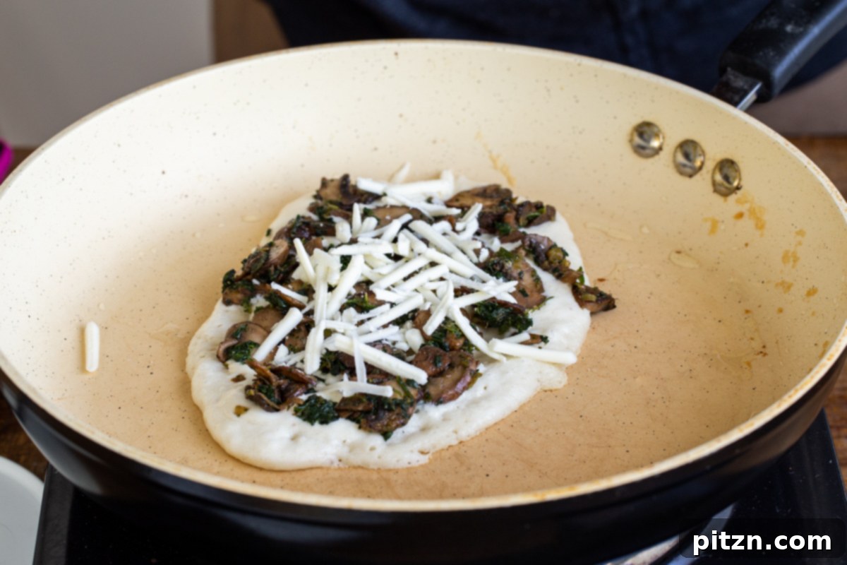 Spinach and Mushroom Stuffed Almond Flour Naan 18 Almond flour naan baking in a pan, topped with mushrooms, spinach, and vegan cheese