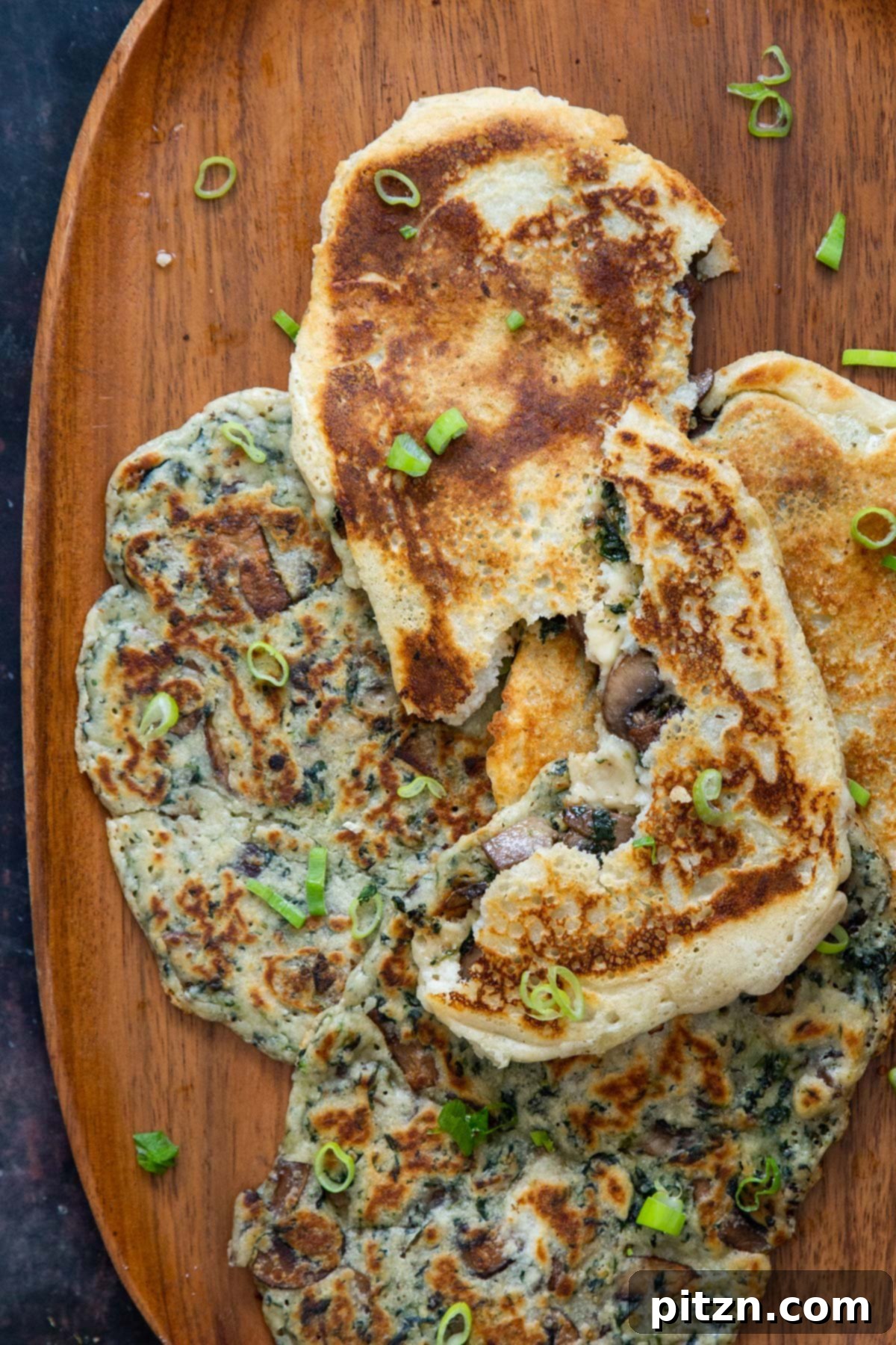 Spinach and Mushroom Stuffed Almond Flour Naan 3 Vegan spinach and mushroom stuffed naan bread on a wooden plate, sprinkled with sliced green onions