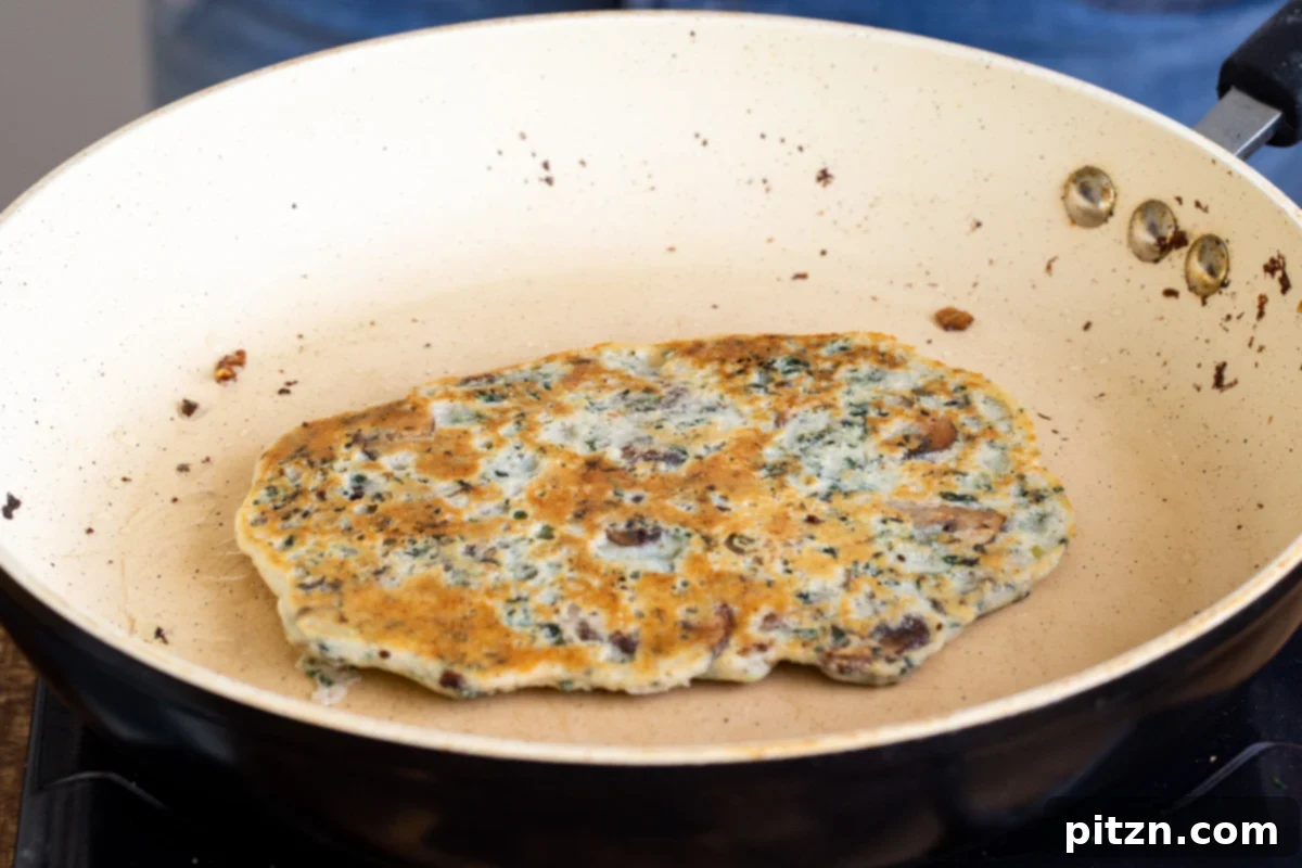 Spinach and Mushroom Stuffed Almond Flour Naan 24 Vegan spinach mushroom naan in a pan after being flipped, cooking on the second side