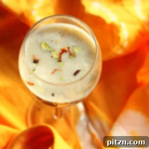 An overhead shot of a glass of thandai on an orange fabric background