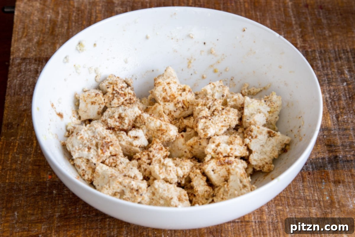 Plant-Based Chicken Changezi 8 Marinated and seasoned tofu chunks arranged on a parchment-lined baking sheet, prepared for baking.