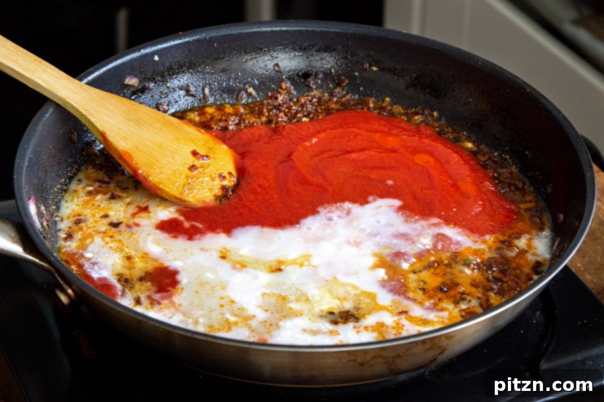 Plant-Based Chicken Changezi 14 Coconut milk blended with tomato puree and spices, simmering to form a rich, creamy gravy in a pan.