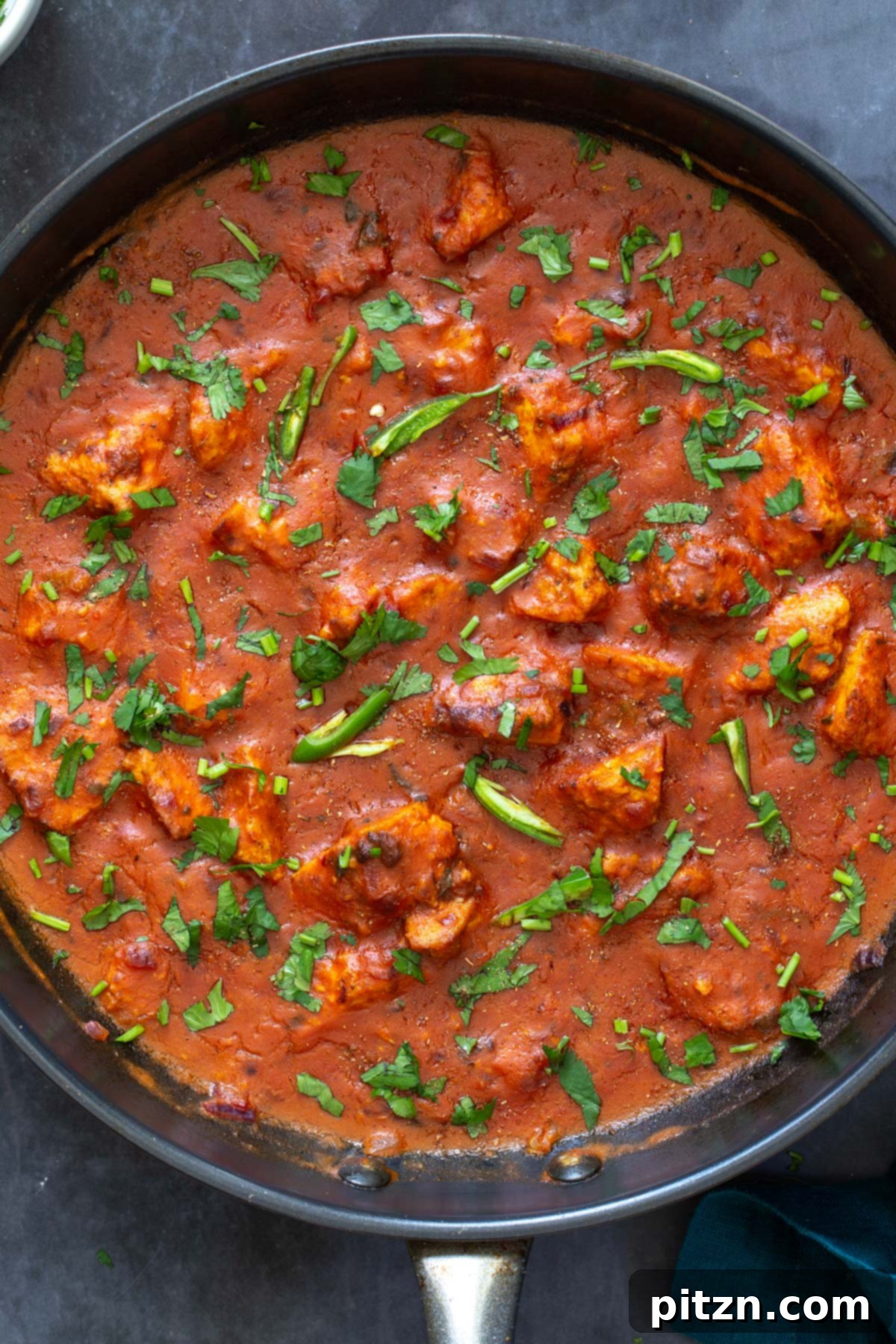 Plant-Based Chicken Changezi 4 Serving of Vegan Chicken Changezi with tofu in a black skillet, garnished with fresh cilantro and green chilies, ready for enjoyment.