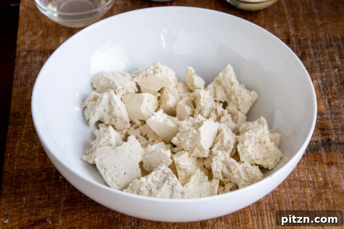 Plant-Based Chicken Changezi 6 Hand-torn firm tofu pieces in a white bowl, ready for marination, illustrating the rustic texture.