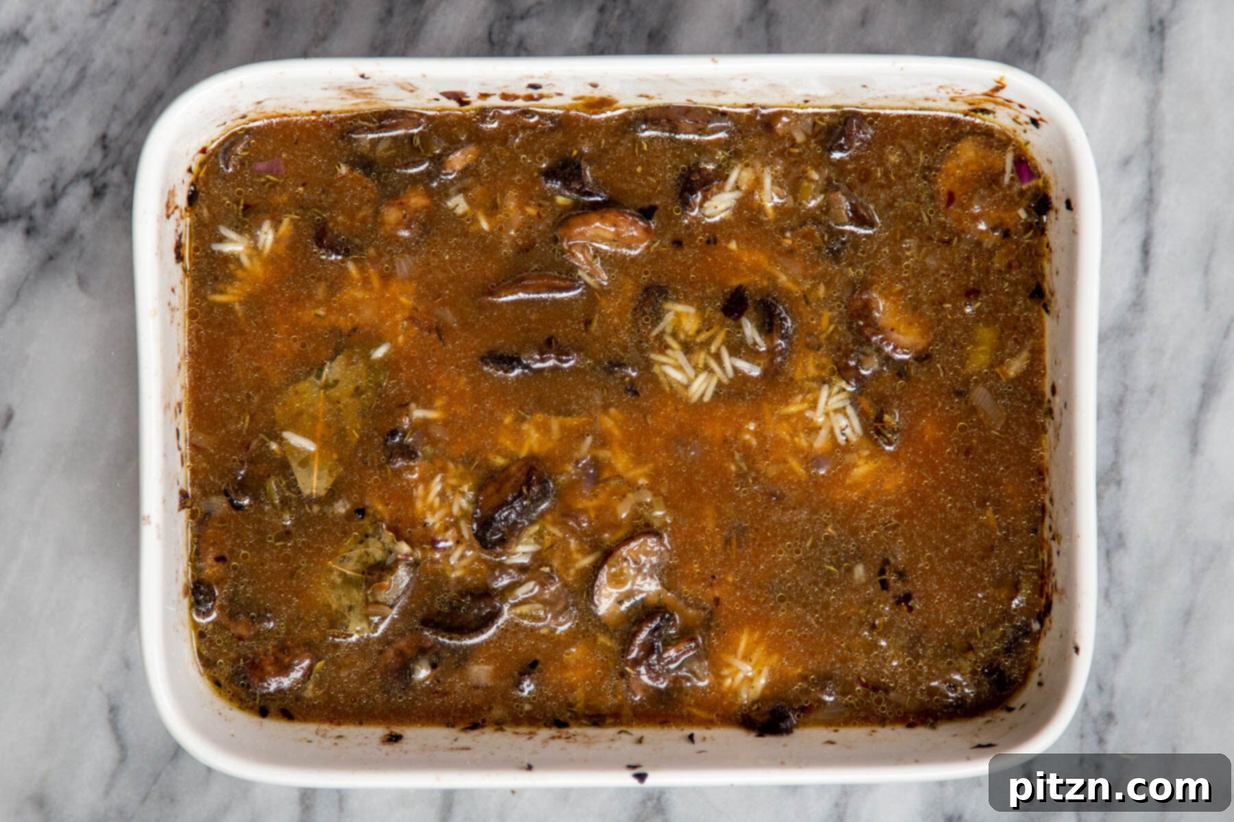 A casserole dish filled with vegan baked mushroom rice, covered and ready to be placed in the oven for cooking.