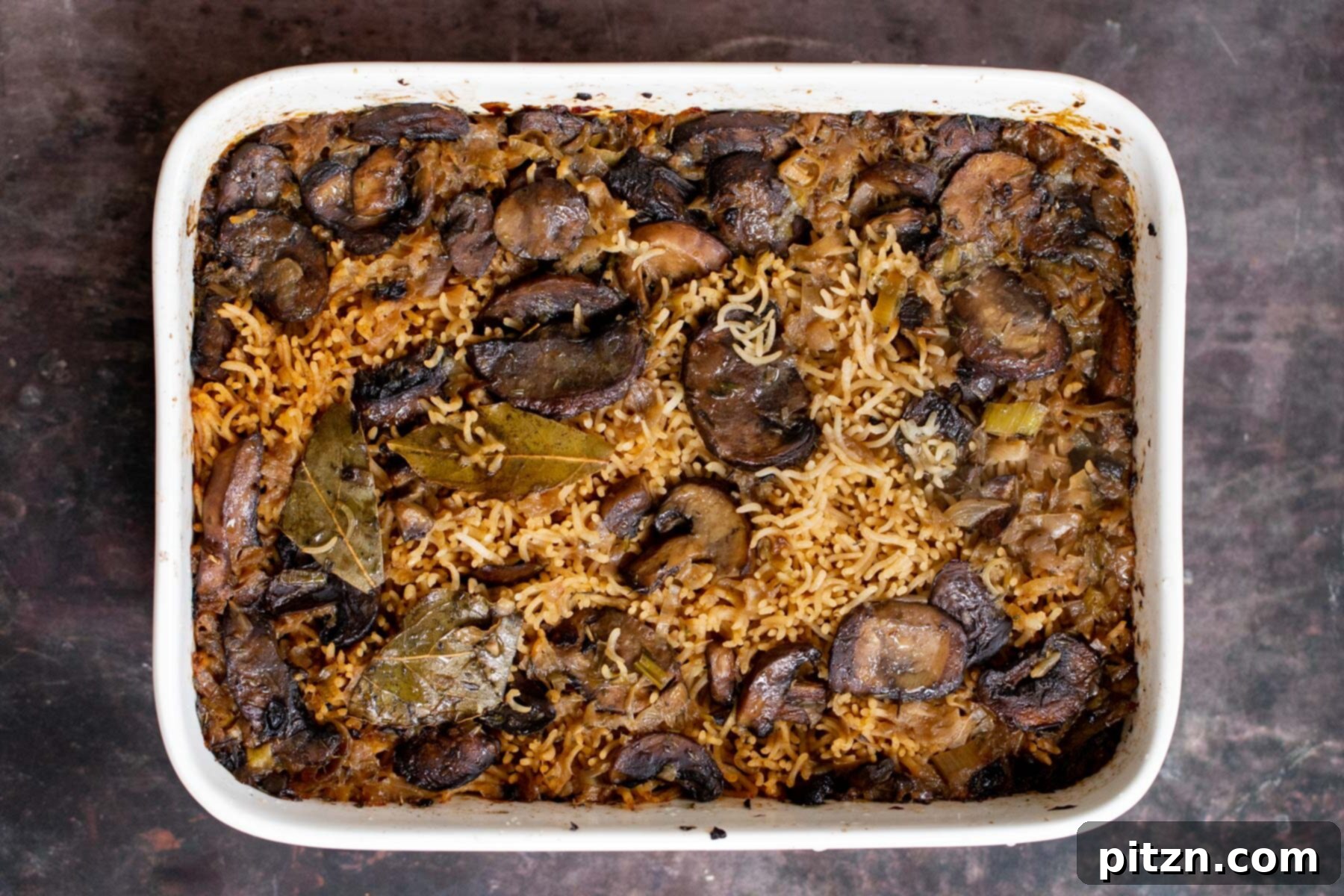 A casserole dish filled with baked mushroom rice, fresh out of the oven, showcasing its moist and cooked texture.