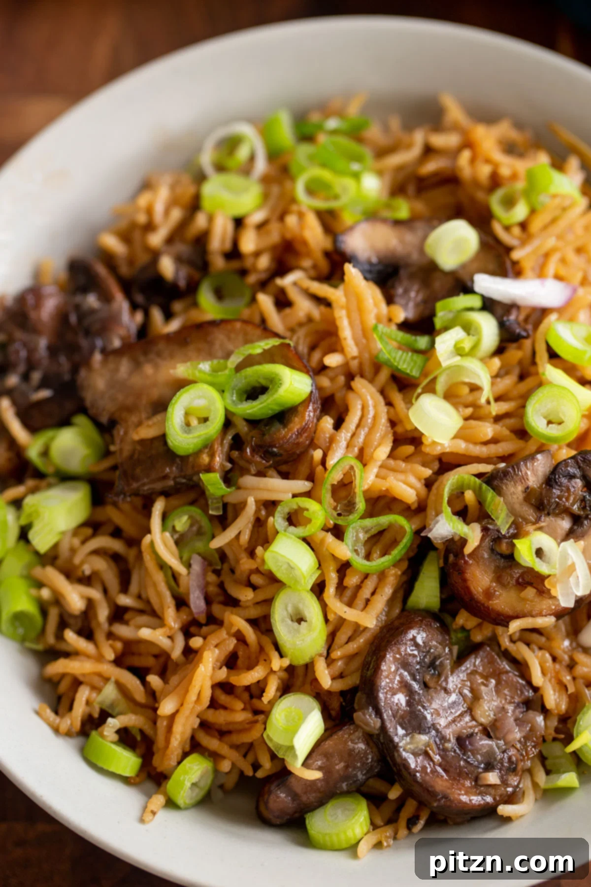 A plate of fluffy mushroom rice, generously garnished with fresh sliced green onions, ready to be enjoyed.